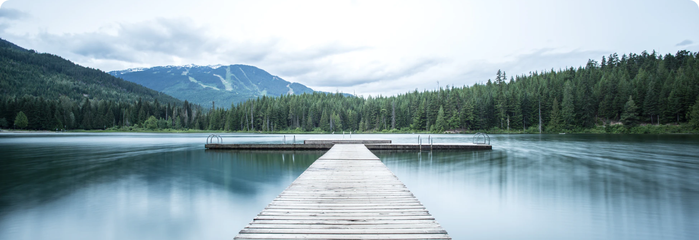 jetty in a peaceful lake surrounded by trees and hills