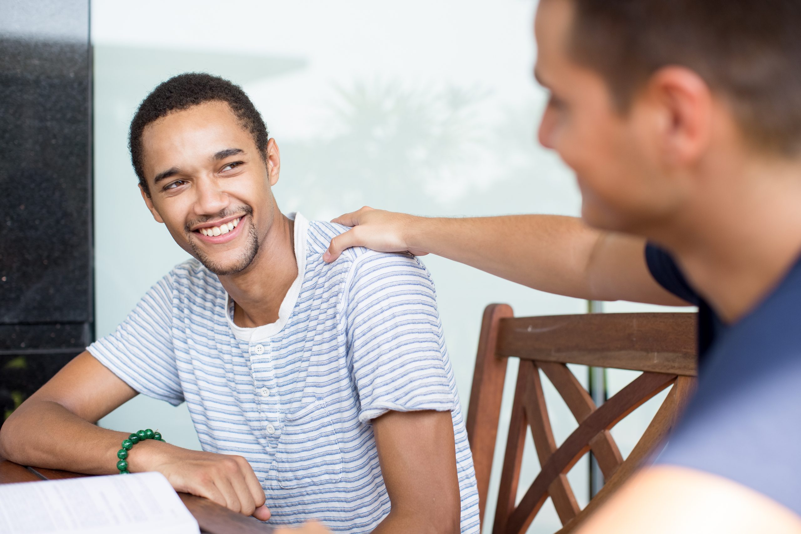 two men talking with one supportively resting his hand on the other's shoulder