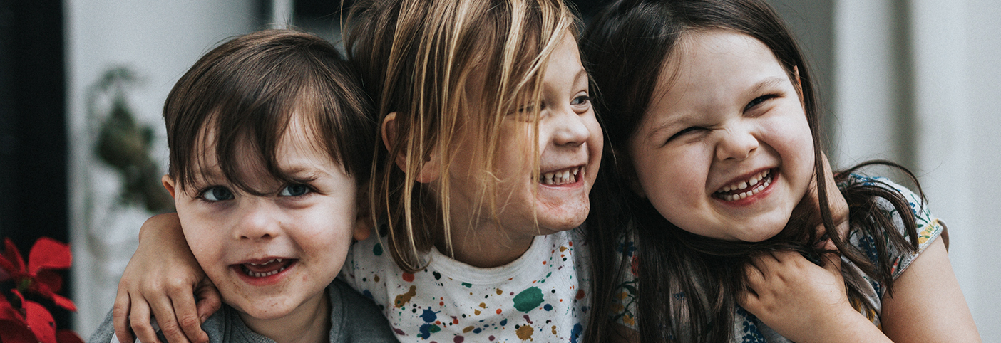 three children smiling and hugging