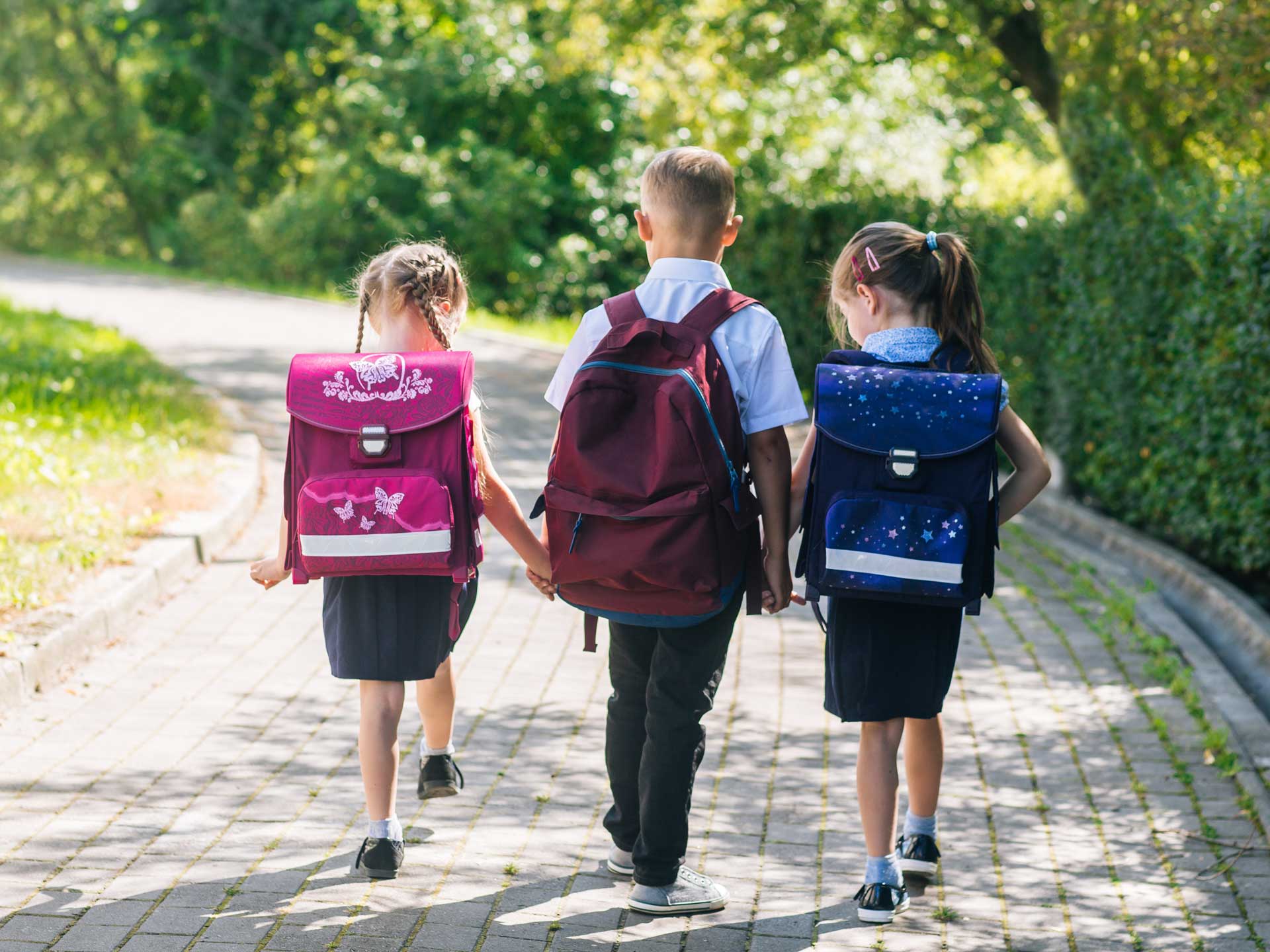three school-children walking with backpacks