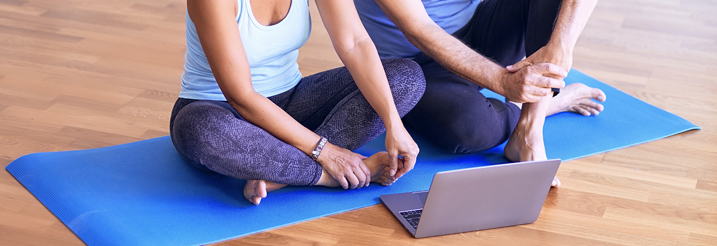 two people on a yoga mat watching a laptop