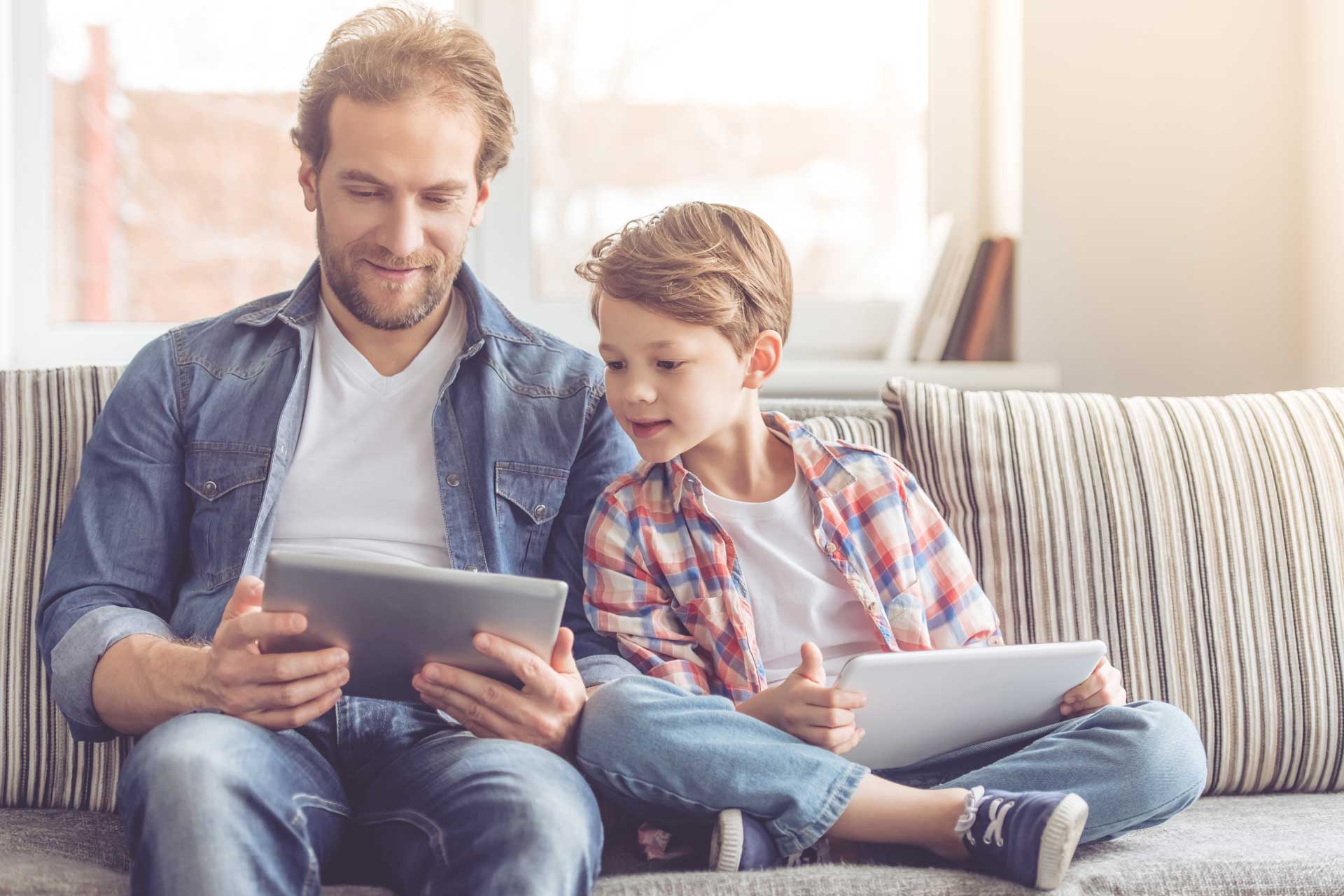 father and son sitting with tablet devices