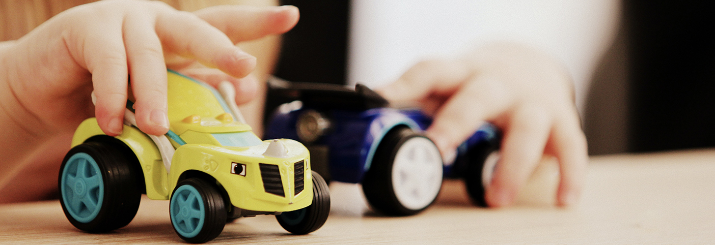 close-up of a baby's hands playing with two toy cars