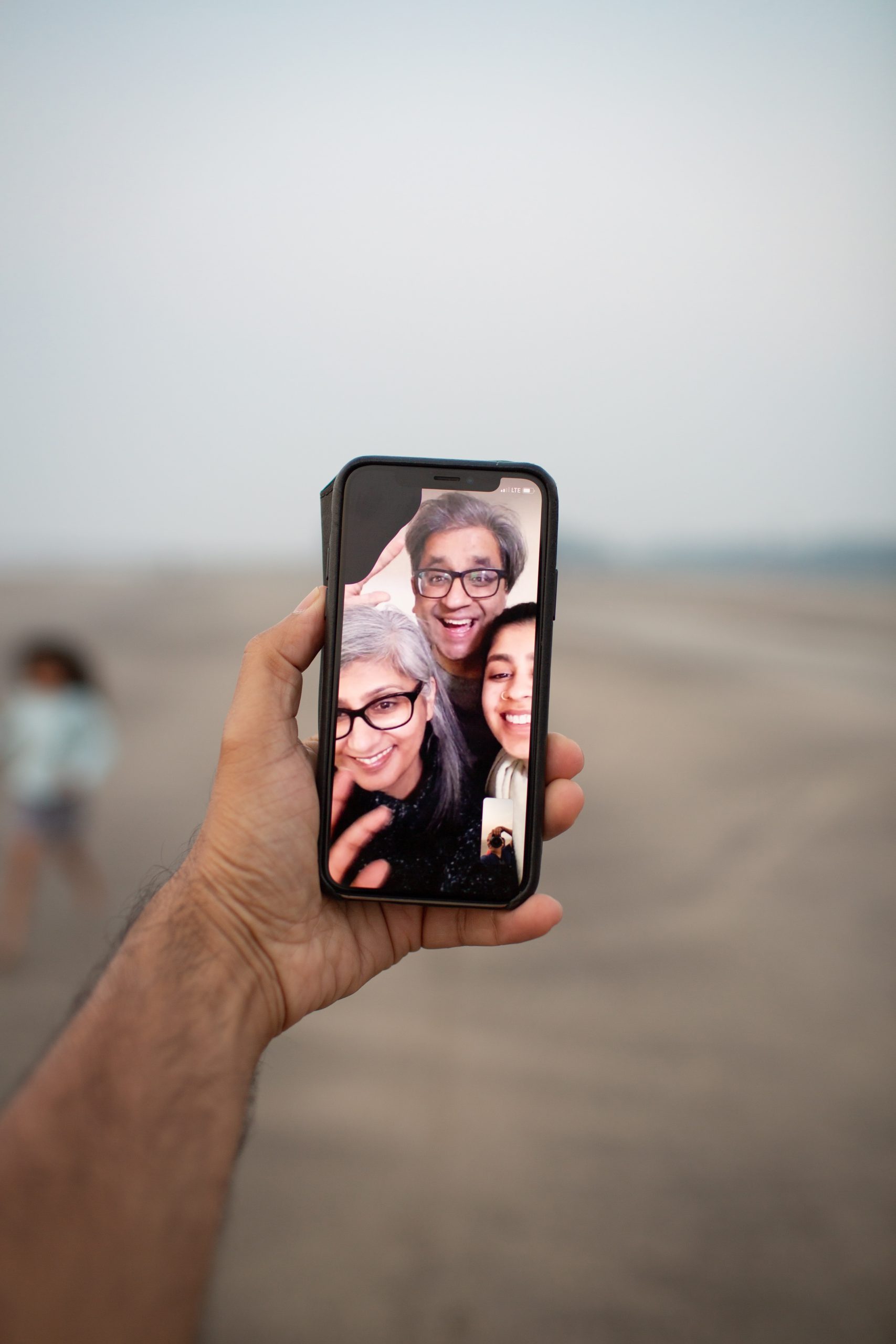 hand holding a mobile phone showing a video call with three family members