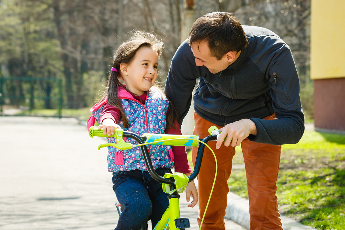 father teaching his daughter to ride a bike