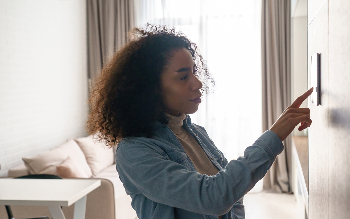 Woman using a thermostat at home