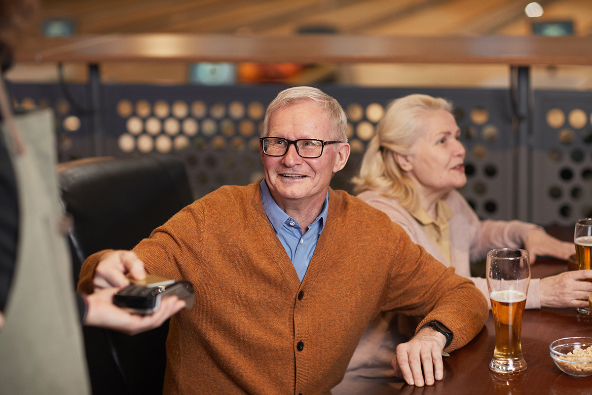 Senior man paying at a bar