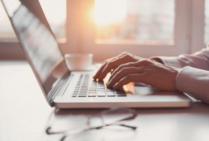 woman using laptop at a desk. Her hands are shown typing