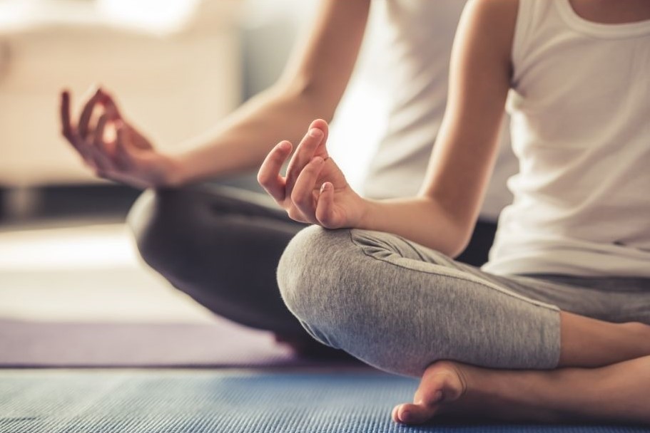 two people doing a seated yoga position. They're legs are crossed and arms are on their laps.