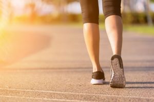 woman's outside walking in the sunshine. The back of her legs are shown as she is stepping forwards.