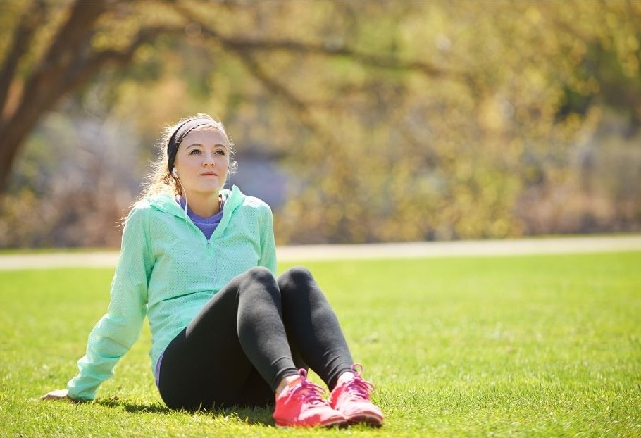 young woman in athletic clothing sitting on the grass in the park