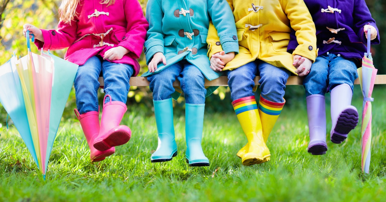 Children sitting in a row wearing differently coloured wellies