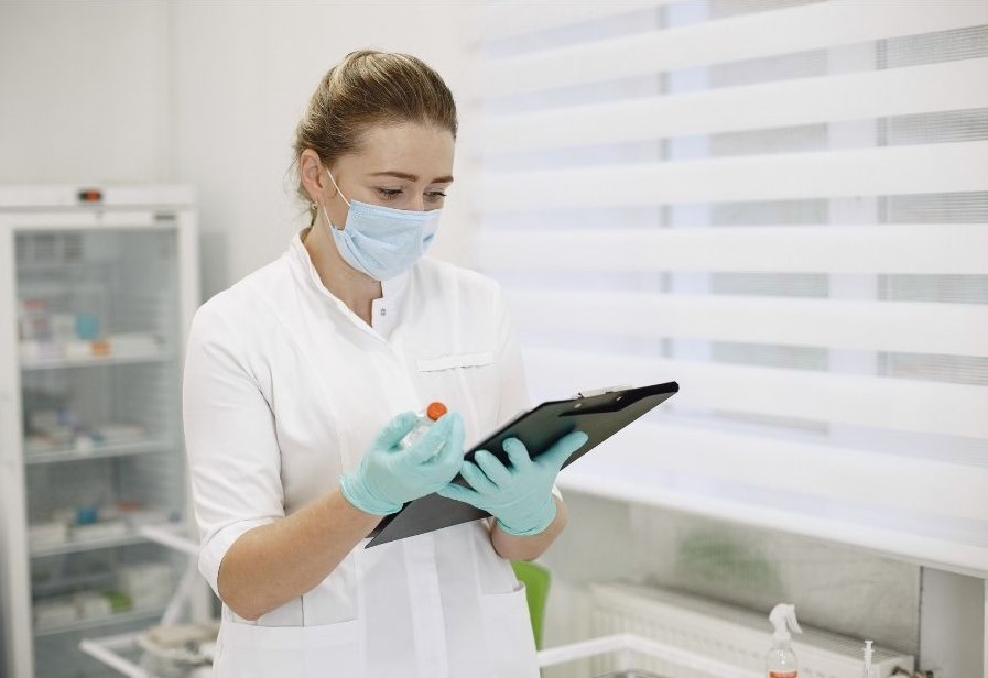 female pharmacist wearing a mask and looking at her notes