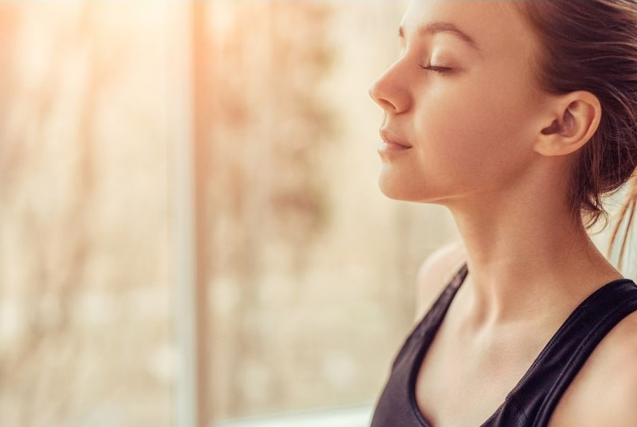 young woman in nature, taking a deep breath with eyes closed