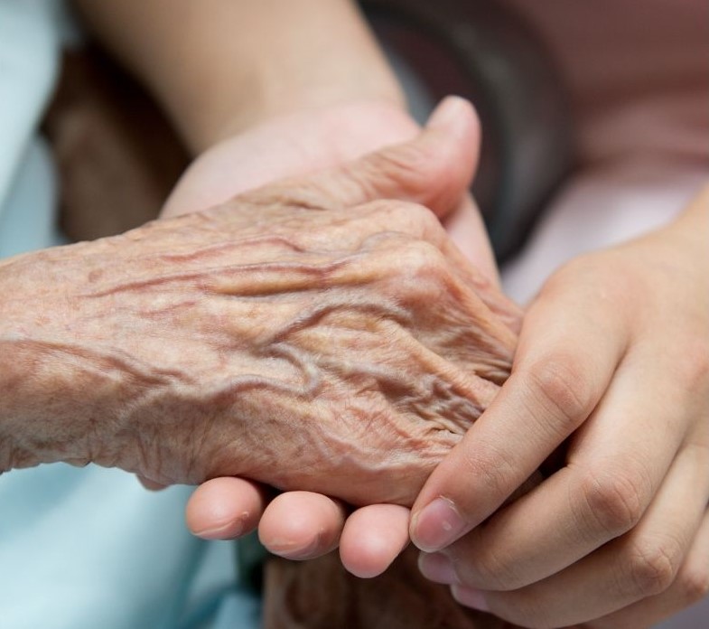 young person holding the hand of an old person