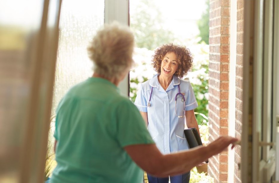 Elderly woman answering the door to a female care worker