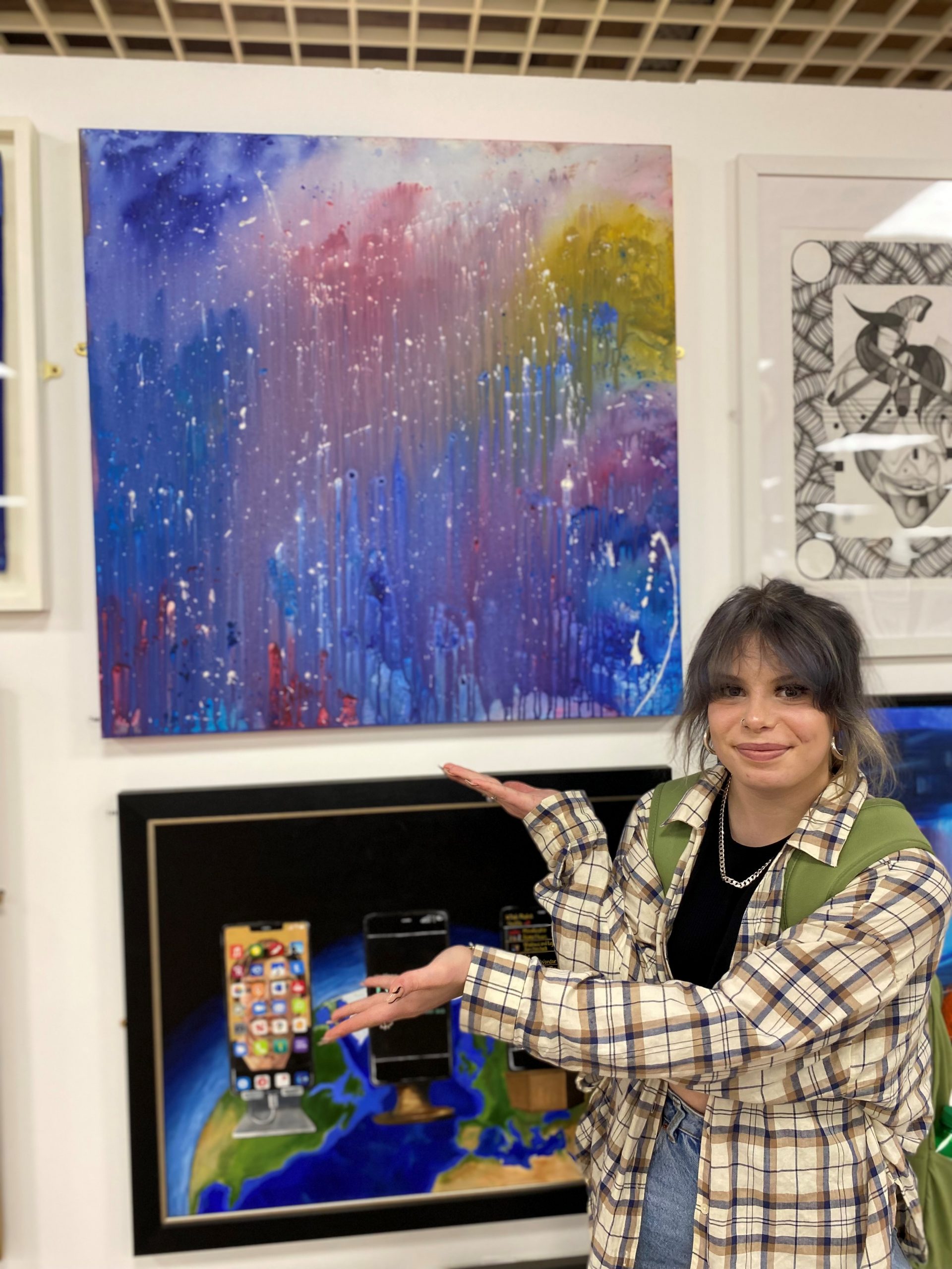 Jam stands beside her artwork in the exhibition area.