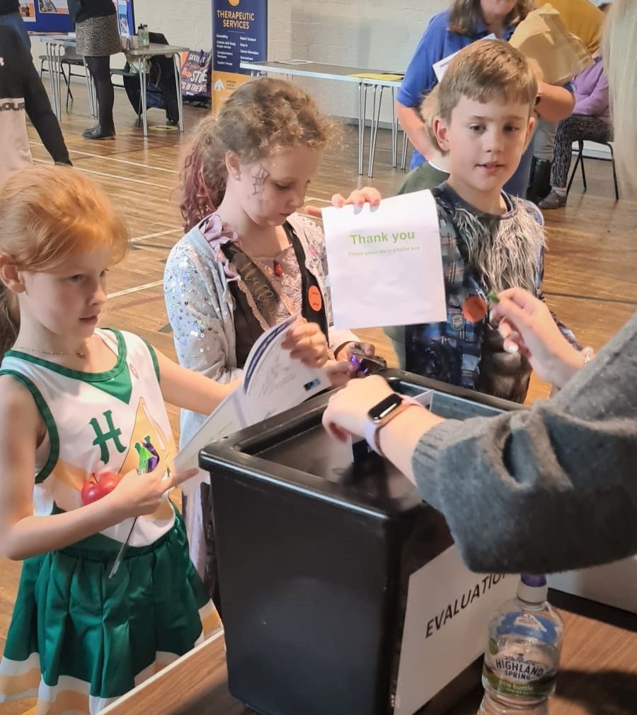 Three young children placing their votes in the ballot box at our Stewarton PB