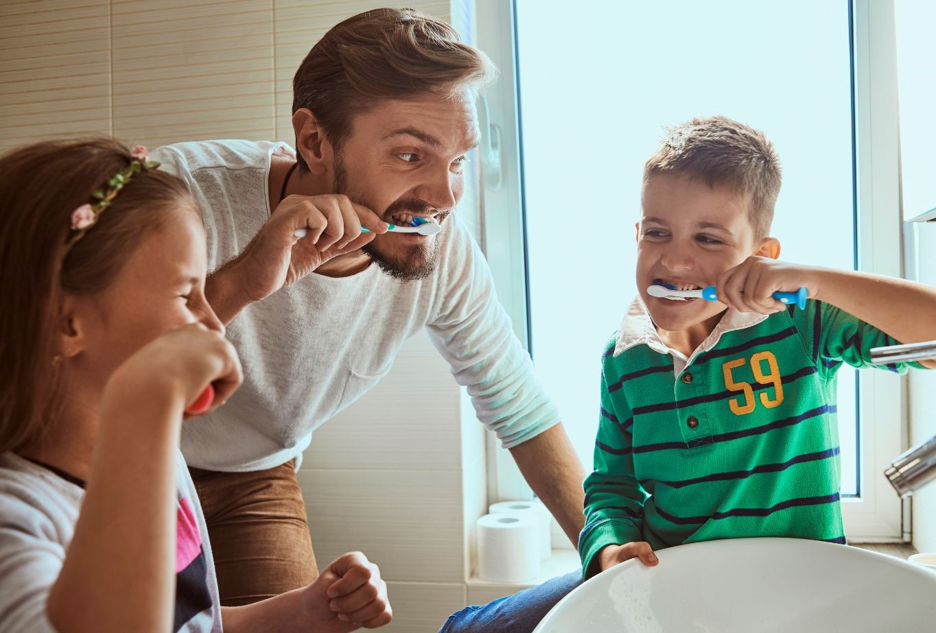 A father and his two children brushing their teeth together