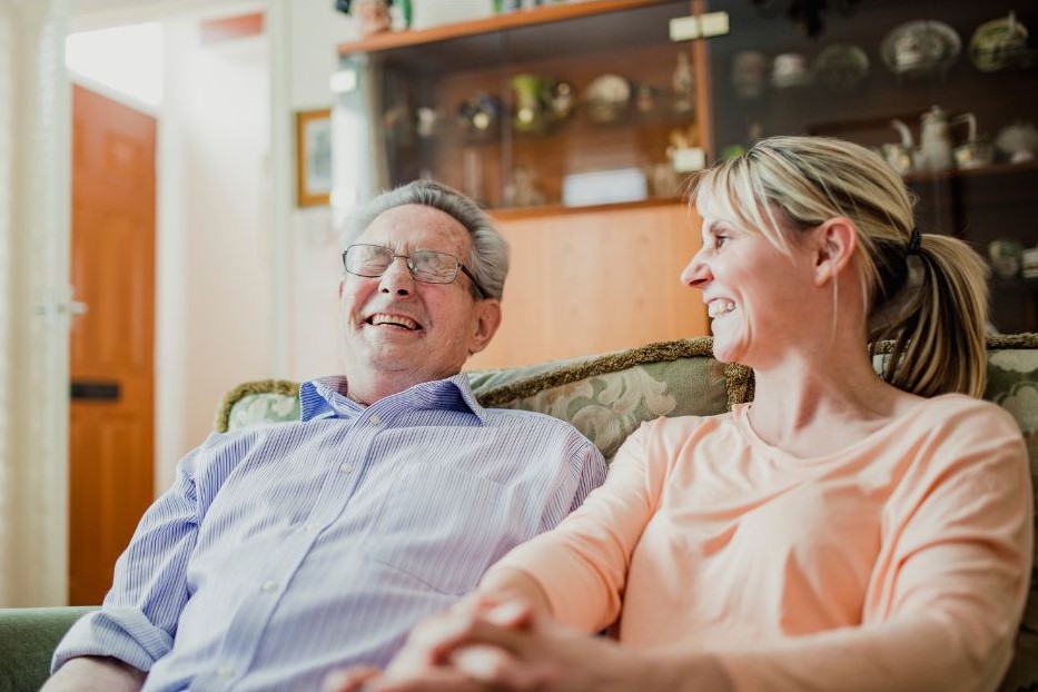 An elderly man and woman sitting together laughing