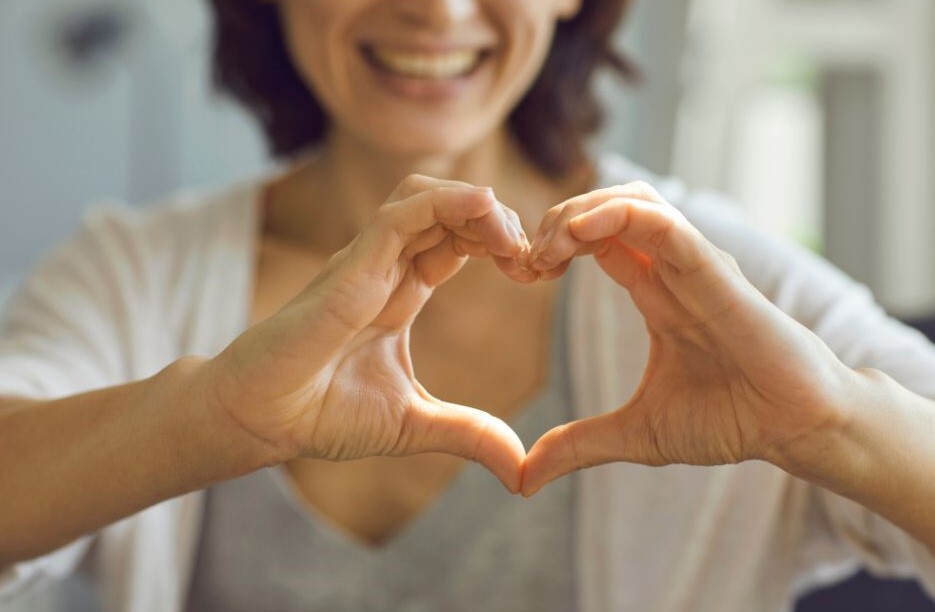 A woman making a heart shape with her hands and fingers