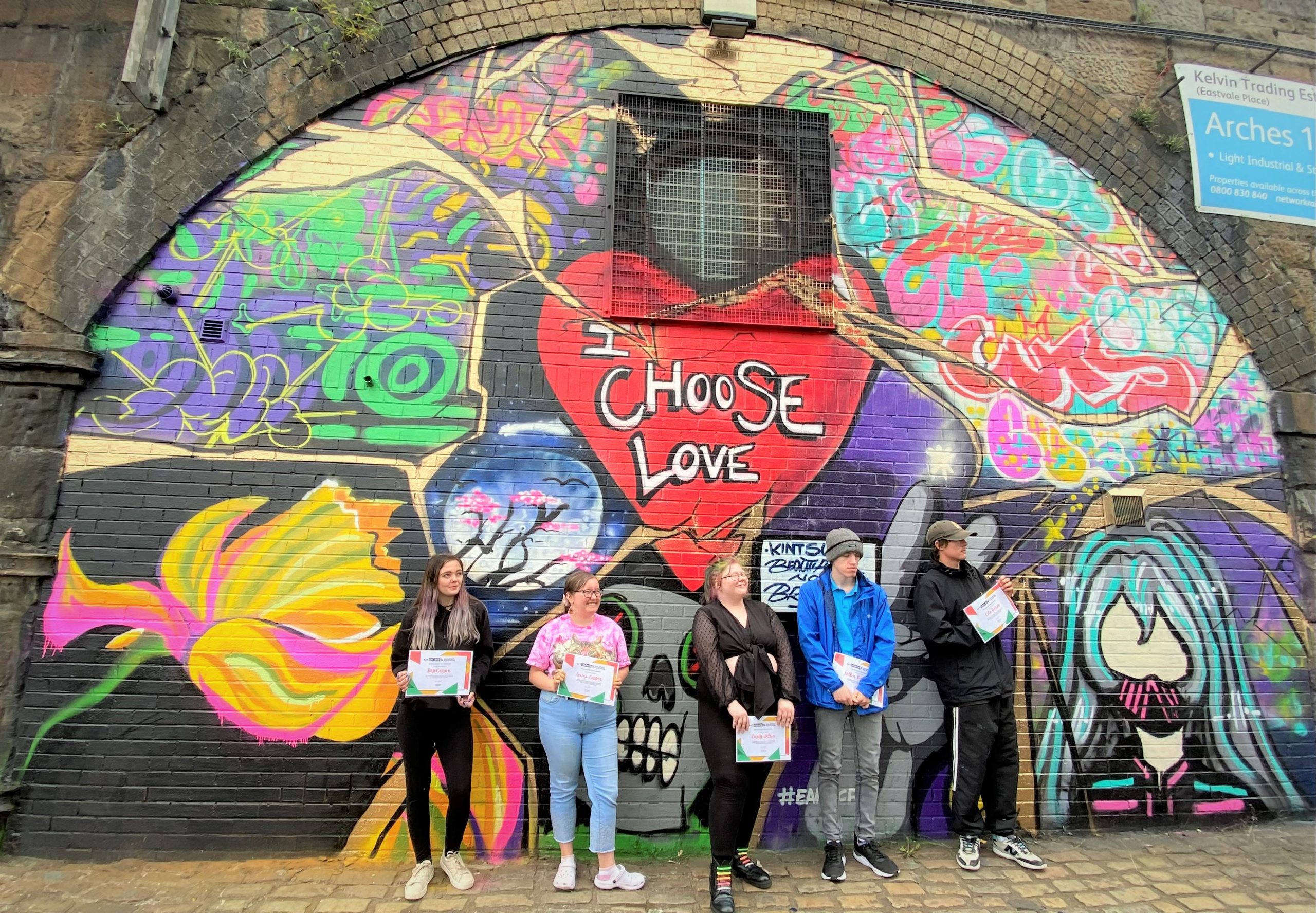 Young people standing in front of their colourful mural