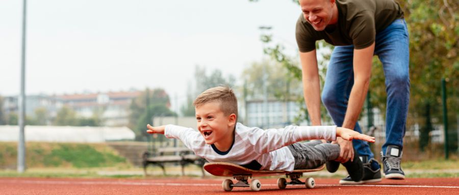 A foster carer with a foster child playing on a skateboard