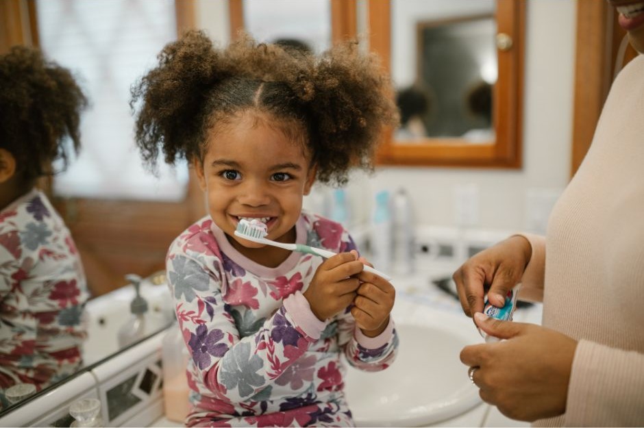 A happy little girl brushing her teeth